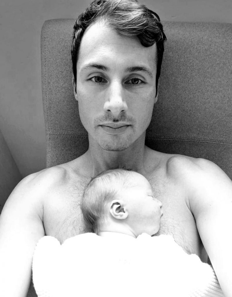 Un père et sa fille bébé couchée sur son torse